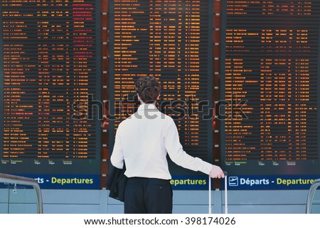 people in the airport, business travel, passenger looking at timetable screen board