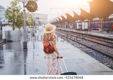 travel by train, woman with luggage waiting on platform of railway station