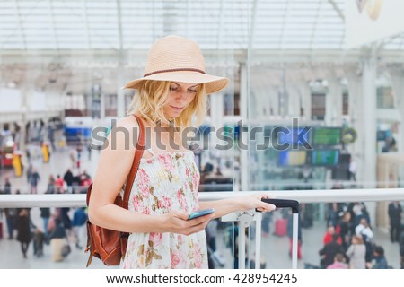 woman in airport checking mobile phone, traveler smartphone app
