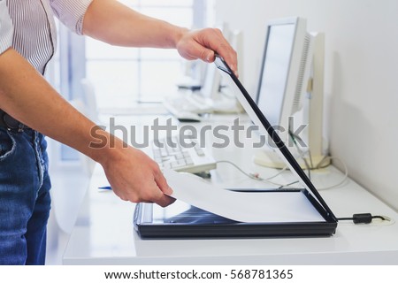 using scanner in office or library, closeup of hands scanning documents