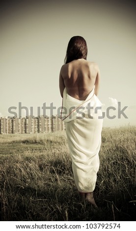 Beautiful naked woman from back outdoors on industrial background