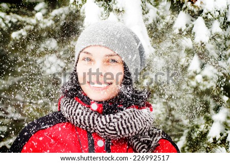 Beautiful winter portrait of young woman with snow falling on her face in the winter snowy scenery