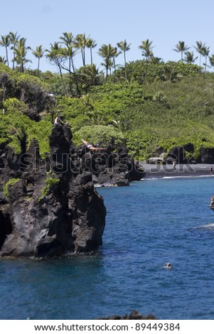 A cliff diver jumps into the ocean at Waianapanapa State Park in Maui