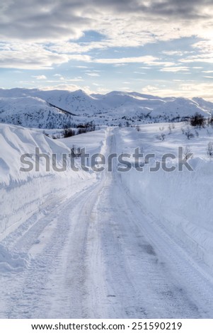 Picture of a road covered with snow, with mountains in the back