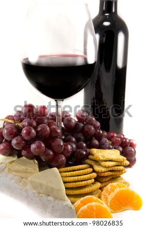 Picture of a bottle of red wine with grapes around, and crackers and clementins