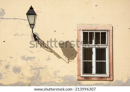 Fragment of the wall with the window and the old iron street lamp.