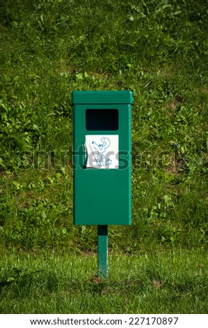 Close up of bright green dog mess poop bin with label.