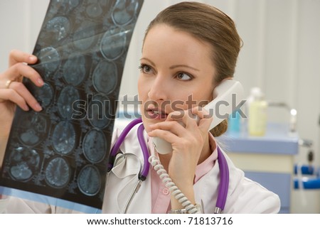 Female doctor looking x-ray scan and talking on phone in diagnostic center
