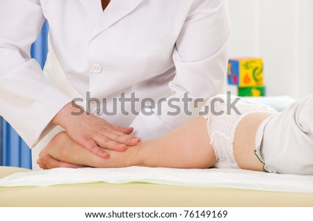 Doctor massaging little baby\'s leg in clinic office