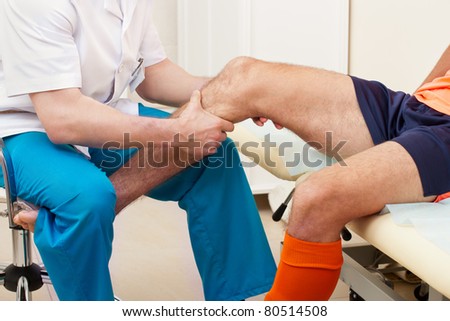 Doctor testing a knee for stability of injured football player in clinic