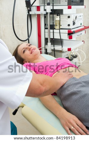 Doctor testing stomach of young woman in clinic