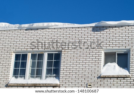 House with snow on roof and window during a sunny day in winter