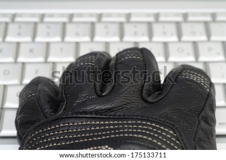 Hacking concept with hand in black leather glove over the laptop keyboard