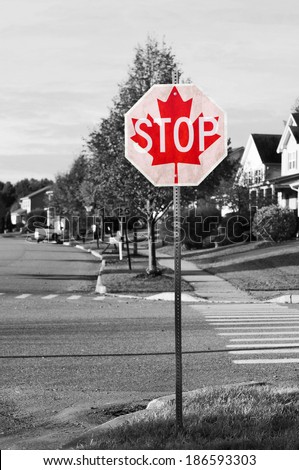 Canadian stop sign concept on black and white street scene with selective color on the stop sign