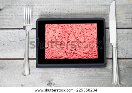 Table setting with fresh raw ground lean beef on a tablet screen