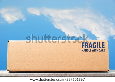 Shipping box with fragile handle with care as notice against blue sky background