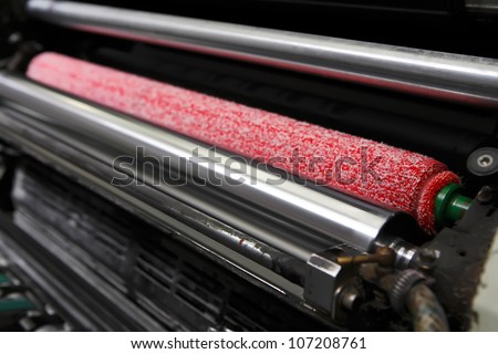 Opened offset printing machine with ink rollers with special red wetting roller. Focused to right side image.