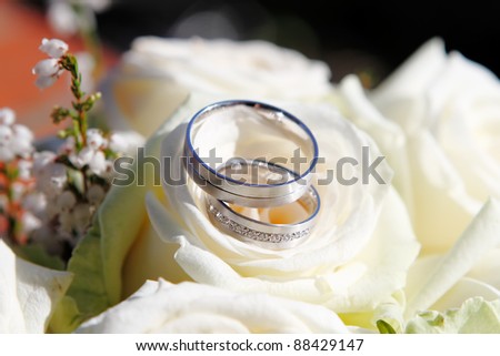 stock photo Detail on wedding rings with white flowers
