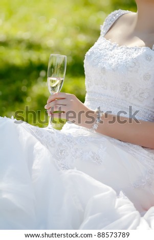 A glass of champagne in the hand of bride in portrait orientation, focused to glass