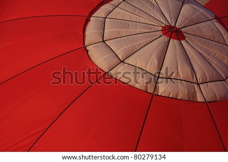 Top portion of a red hot air balloon, showing the circular parachute valve.