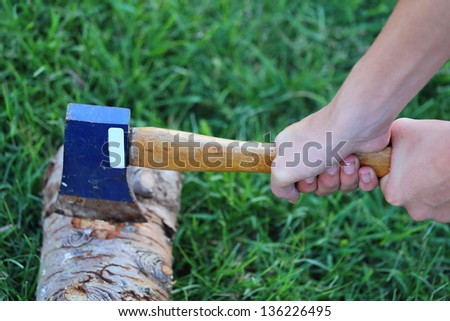 Close up view of someone using a hatchet with both hands to cut through a log