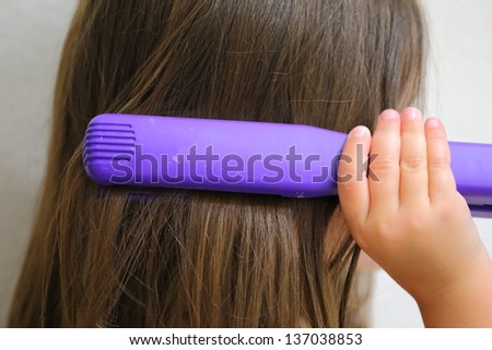 Close up view of a young girl straightening her hair