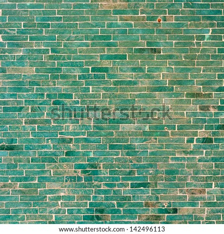 Turquoise tiled brick wall with an interesting irregular texture.
