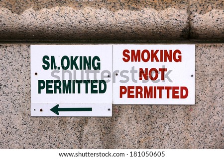 Two signs marking the border between the smoking and the non-smoking area outside a building.