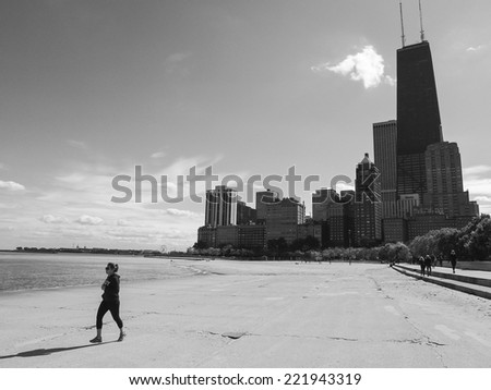 CHICAGO, IL, USA - OCTOBER 5, 2014: Woman runs along the beach of the Chicago Gold Coast with downtown skyscrapers in the background in Chicago, IL, USA on October 5 2014.