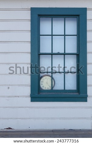 An old clock lies forgotten behind a window.