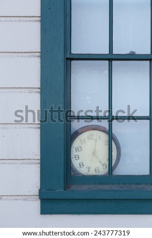 An old clock lies forgotten behind a window.