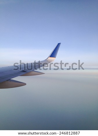 View from a jetliner of its right wing over creamy smooth clouds.