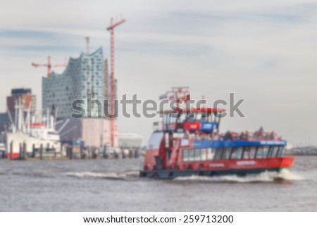Blurred background of Hamburg harbor ferry passing by landmark Elbe Philharmonic construction site.