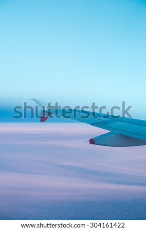 View out an airplane window past its left wing on a beautiful summer evening above Europe.