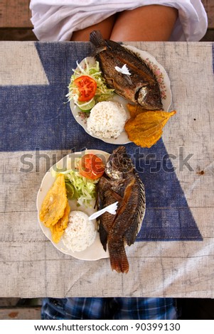 Top-down view of a simple but savory caribbean seafood lunch set out on a beachside table.