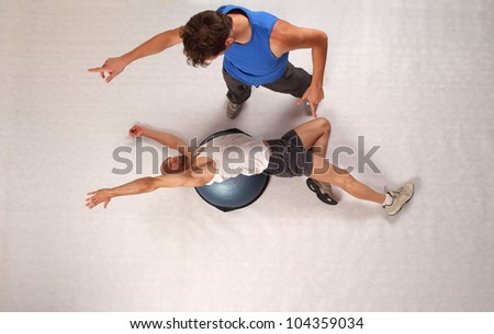 Overhead view of bold man man training with personal trainer on hemisphere