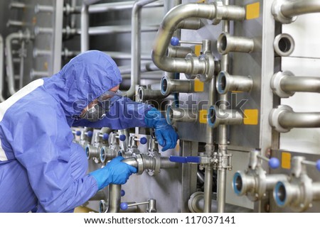 Technician in blue,protective uniform,mask and goggles fixing valves in plant