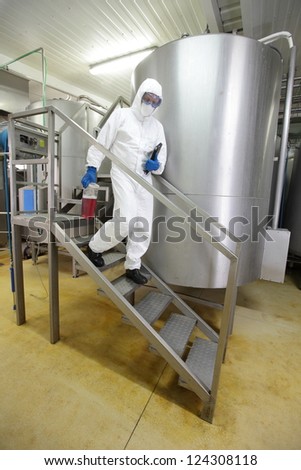 engineer with tablet and  sample in plastic container walking down the stairs  in industrial interior