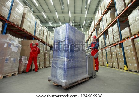 logistics management of the flow of resources two workers in uniforms and safety helmets working in storehouse logistics management of the flow of resources two workers in uniforms and safety helmets working in storehouse