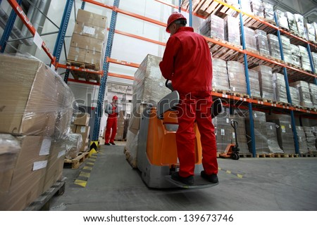 logistics - Goods delivery - two workers working in storehouse with forklift loader