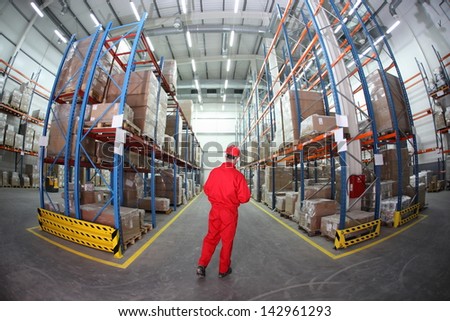 Worker in hard hat and red uniform in warehouse - back view