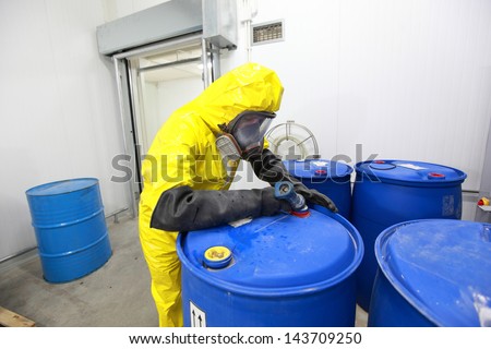 Professional in uniform filling barrels with chemicals
