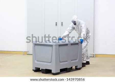 fully protected technician at plastic container in modern industrial environment