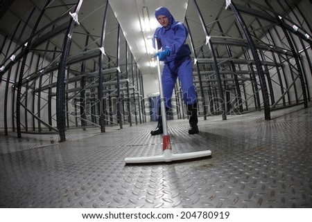 worker in blue protective uniform cleaning floor in empty storehouse fish eye lens worker in blue protective uniform cleaning floor in empty storehouse fish eye lens