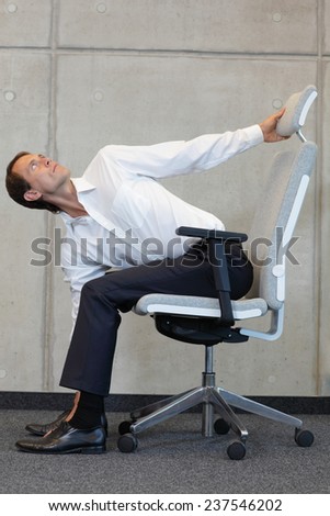 yoga with arm chair in office - business man exercising