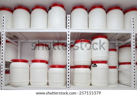 white chemical plastic barrels on shelves in storehouse