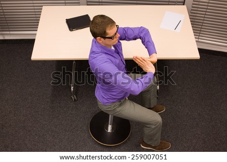 male office worker,exercising during short break in work at his desk in office