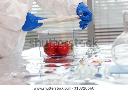 Scientist dressed in protective gear working with vegetables in lab - close up