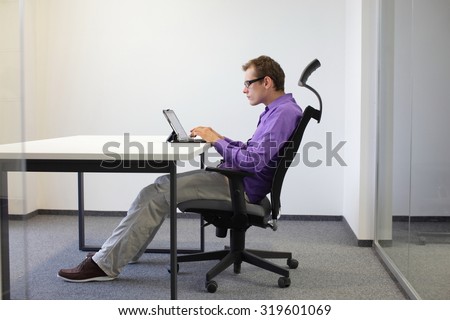 text neck - man in slouching position on ergonomic chair working with tablet at desk