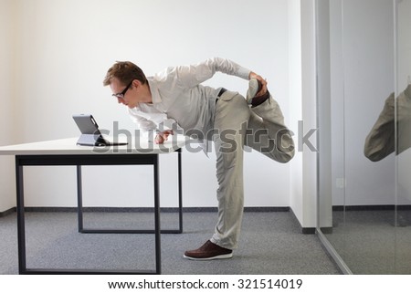 leg exercise during office work - standing man reading at tablet in his office